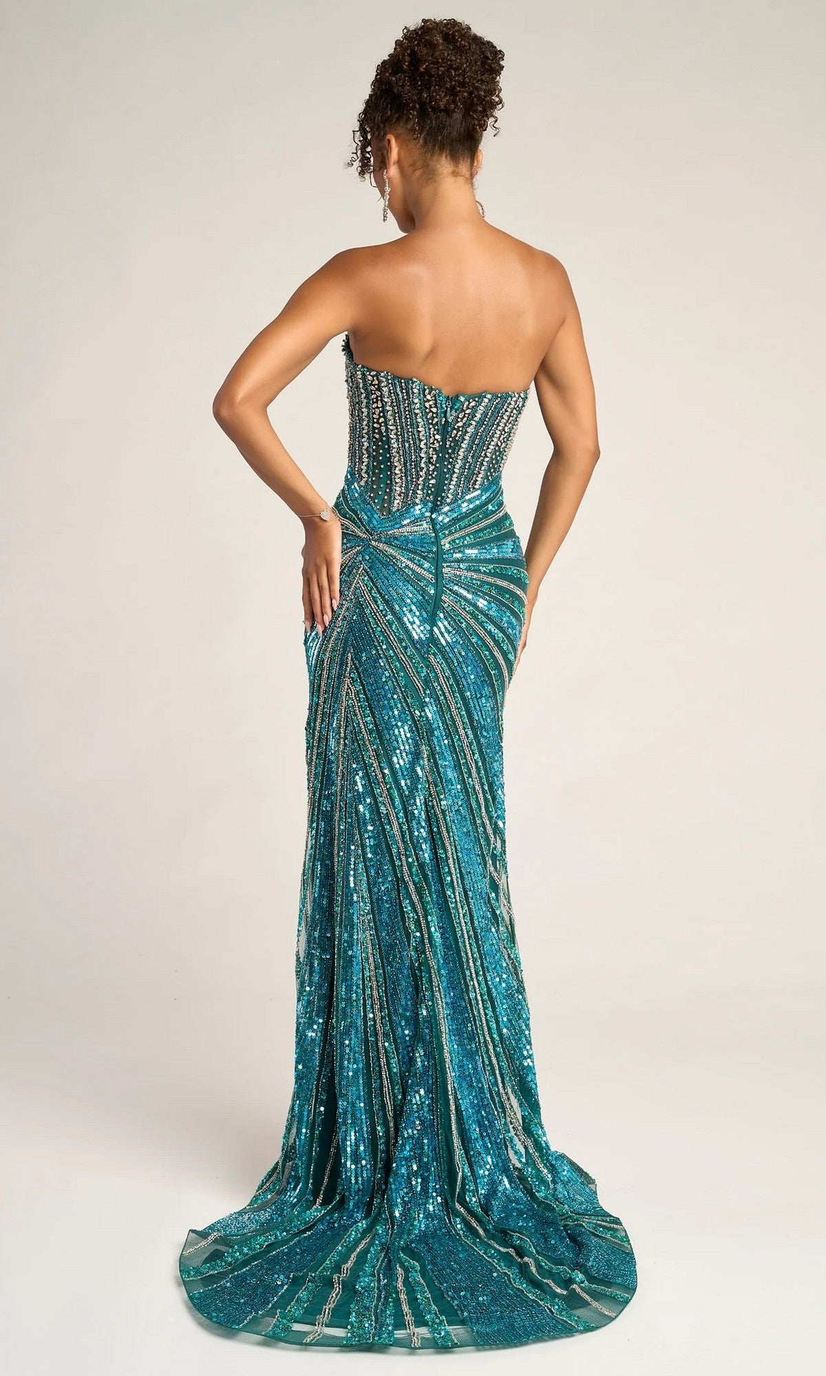 A woman faces away, wearing the Portia and Scarlett PS26431C— a strapless, floor-length teal formal dress with beading, sequins, intricate patterns, and a high leg slit.